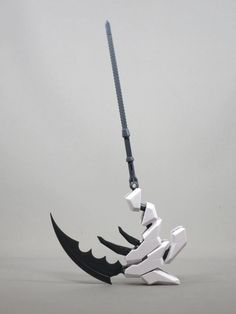 a white and black toy is hanging from a hook on a gray background with an arrow in the shape of a bird