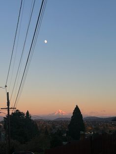 the sun is setting over a city with power lines and telephone poles in the foreground