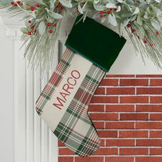 a christmas stocking hanging from the side of a brick wall next to a wreath