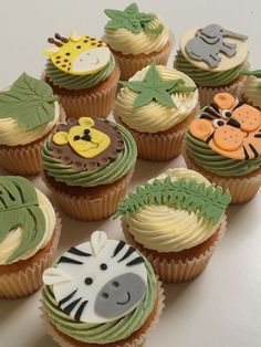 there are many cupcakes decorated with animals and leaves on top of each one