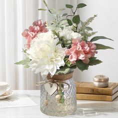 a vase filled with flowers on top of a table next to a cup and saucer