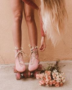 a woman standing on roller skates next to flowers