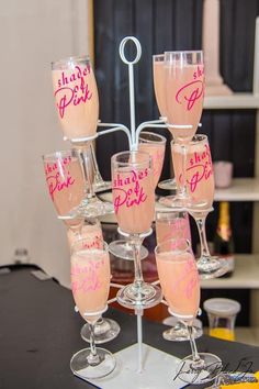 there are many wine glasses that have pink lettering on them, and one is filled with champagne