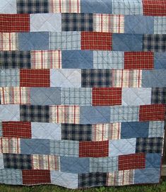 a blue and red patchwork quilt on the grass