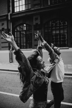 two people standing on the side of a road with their arms in the air