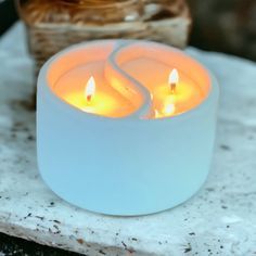 two lit candles sitting on top of a marble slab