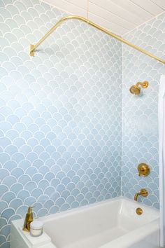 a white bath tub sitting next to a toilet under a faucet in a bathroom