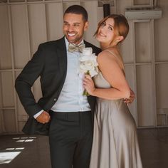 a man in a tuxedo standing next to a woman wearing a dress and bow tie