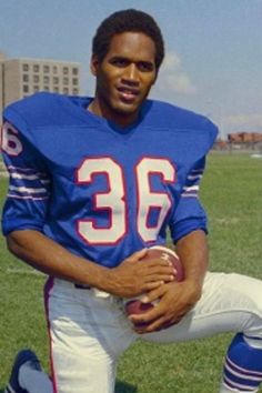 a man kneeling down holding a football on top of a field