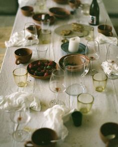 the table is set with wine glasses, plates and other items for eating or drinking