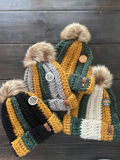 two knitted hats with fur pom - poms on top of each other