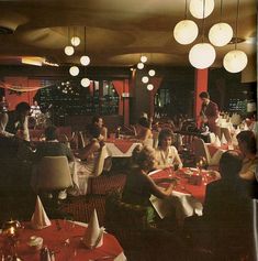 people sitting at tables in a restaurant with red and white tablecloths on them