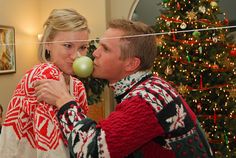 a man and woman kissing in front of a christmas tree