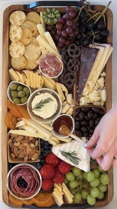 a platter filled with cheese, crackers, grapes, nuts and olives