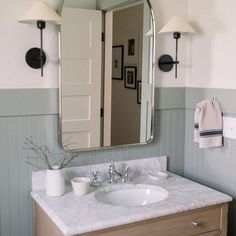 a bathroom sink sitting under a large mirror next to a wall mounted faucet