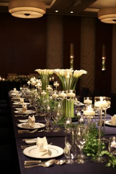 a long table is set with white flowers, candles and place settings for an event