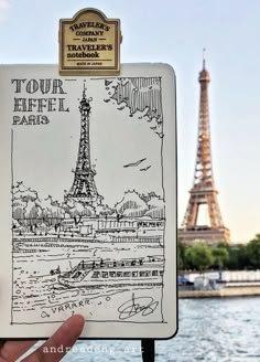 a hand holding up a travel book with the eiffel tower in the background