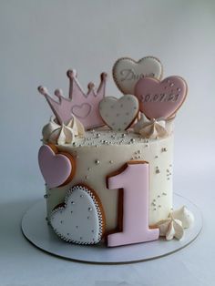 a birthday cake decorated with hearts and a tiara on the top is for one year old