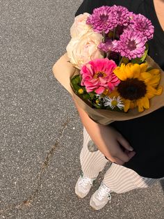 a woman holding a bouquet of flowers on the street