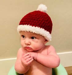 a baby wearing a santa hat sitting in a green pot