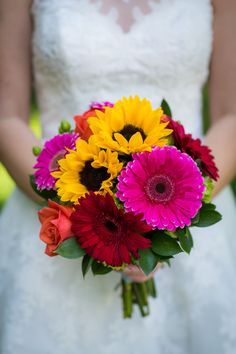 a bride holding a bouquet of colorful flowers