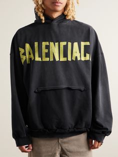 This hoodie features Balenciaga's 'Tape Type' logo, designed to imitate a cool, DIY project. It's cut for an oversized fit from fleece-back cotton-jersey and has a 'ripped' kangaroo pocket for a heavy dose of the label's iconic distressing. Oversized Winter Hoodie With Logo, Oversized Hoodie Sweatshirt With Logo Detail, Urban Oversized Hoodie With Logo Print, Oversized Urban Hoodie With Logo Print, Urban Hoodie Sweatshirt With Logo, Oversized Logo Sweatshirt For Streetwear, Logo Athleisure Hoodie, Streetwear Hoodie With Logo Detail For Winter, Black Hoodie With Logo For Streetwear