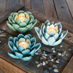 three candles sitting on top of a wooden table next to rocks and pebbles in front of them