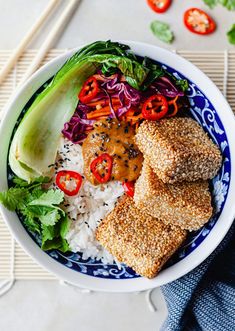 a bowl filled with rice, meat and veggies next to chopsticks