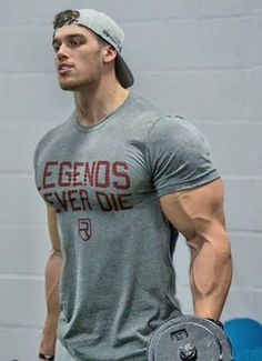 a man in grey shirt and hat holding a dumbbell