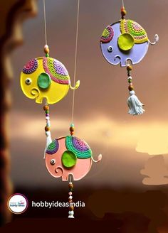 three colorful ornaments hanging from strings in front of a cloudy sky with the words hobydes india on it