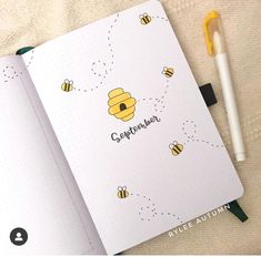 an open notebook with bees on it next to a pen