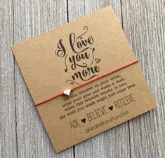 a brown card with a red string attached to it that says i love you more