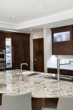 a large kitchen with marble counter tops and wooden cabinetry, along with stainless steel appliances