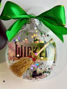 a glass ornament with a broom and glitters on the bottom that says luck