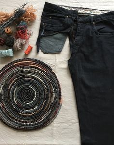 a pair of black jeans next to a basket and yarn