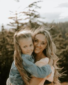 two girls hugging each other in front of trees