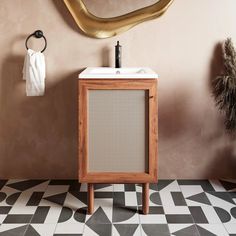 a bathroom with black and white tile flooring and a gold mirror on the wall