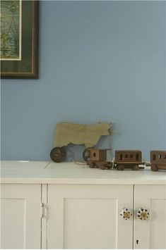 a toy train set sitting on top of a white cabinet next to a framed painting