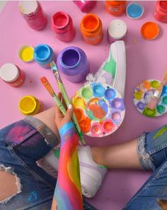 a person sitting on the ground with paint and brushes in their hands next to them