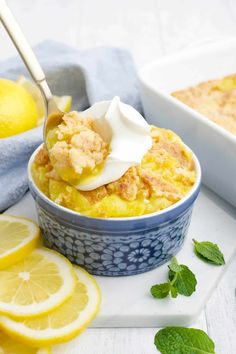 a bowl filled with lemon custard and topped with whipped cream next to sliced lemons