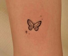 a small butterfly tattoo on the back of a woman's leg, with stars around it