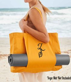 a woman carrying a yoga mat bag on the beach with her hands behind her back