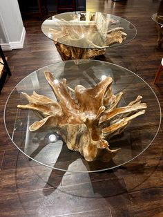 two glass tables with wood pieces on them sitting on a hard wood floor in a living room