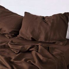 a bed covered in brown sheets and pillows