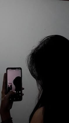 a woman holding up her cell phone to take a selfie with the image on it