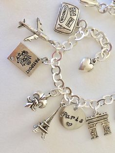 "Adorable Paris charm bracelet featuring 13 detailed silver charms of travel to Paris, classic landmarks, artist quarter, food and drink. Hand stamped 1/2\" 18 aluminum disc says \"Paris ❤️\". Memories of a visit abroad living \"la bonne vie\" in the magical city of Paris! Charms include: suitcase, plane, passport, fleur de lis, Eiffel Tower, Arc de Triumph, artist palette, Sacre Coeur church, Vespa scooter, baguette, cheese, wine, and croissant. Charms are antique silver, pewter and silver tone London Passport, Paris Charm Bracelet, Travel To Paris, Paris Honeymoon, Paris Souvenirs, Cheese Wine, Red Sea Glass, Magical City, Vespa Scooter