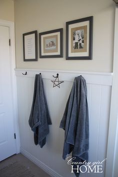 two towels hanging on the wall in front of a door with three pictures above it