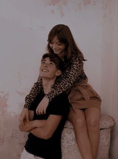 a woman sitting on the back of a man who is hugging him with his arms around her