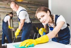 two people in uniform cleaning a table with yellow gloves and green mitts on it