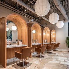 the interior of a hair salon with chairs and lights hanging from the ceiling above them